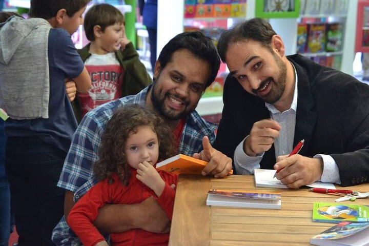 firmando ejemplares de "En el corazón de la lluvia" y "La media izquierda del campeón", de SM.